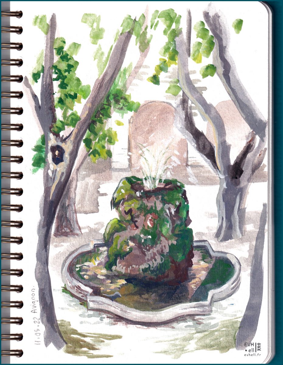 Fontaine avec un gros rochre verdoyant, entourée d'arbres